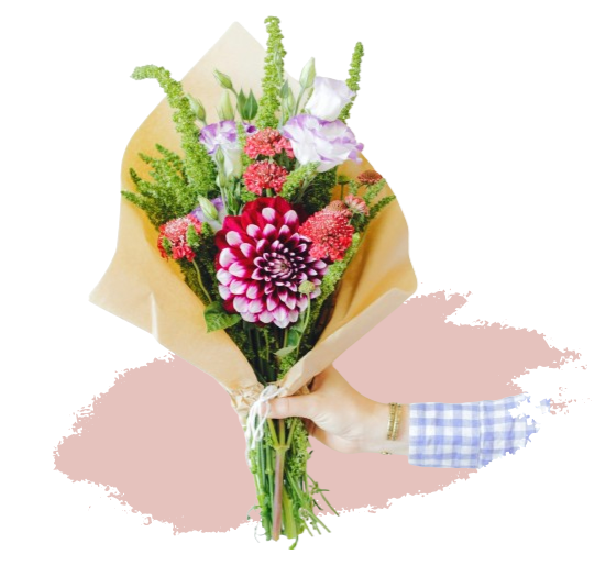 Bouquet de fleurs colorées emballé, tenu par une main.